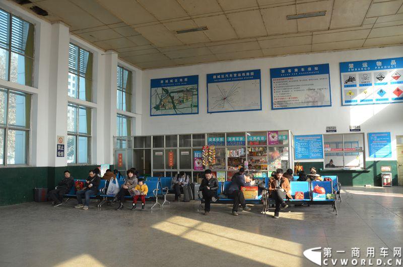 午后的阳光透过候车大厅的窗户，照在候车乘客身边或大或小的礼盒上，散发着一丝丝过年的暖意。 