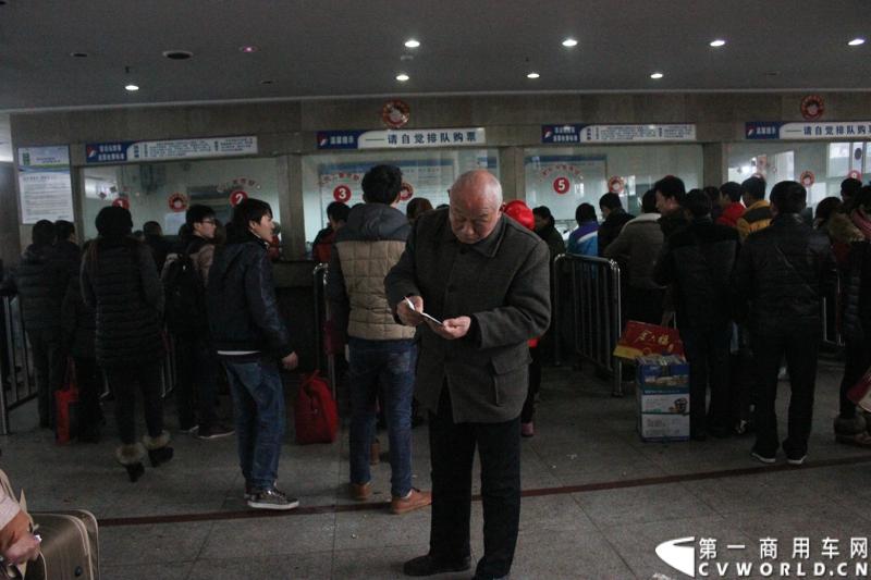 一位老人为儿女买到票后仔细检查车票的正确与否。