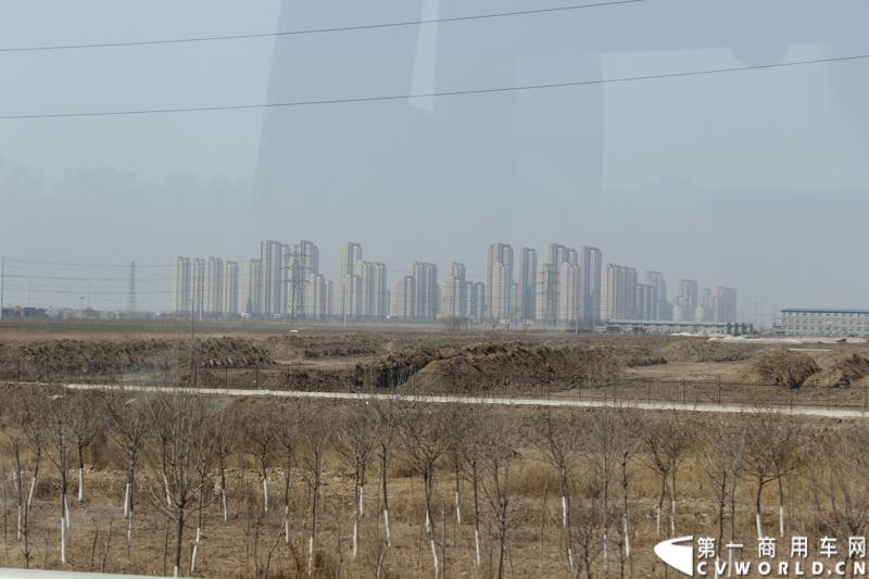 在山海关服务区稍作休整后，奔驰卡车继续南下。远处的楼群是天津大港地区新奇的建筑群。